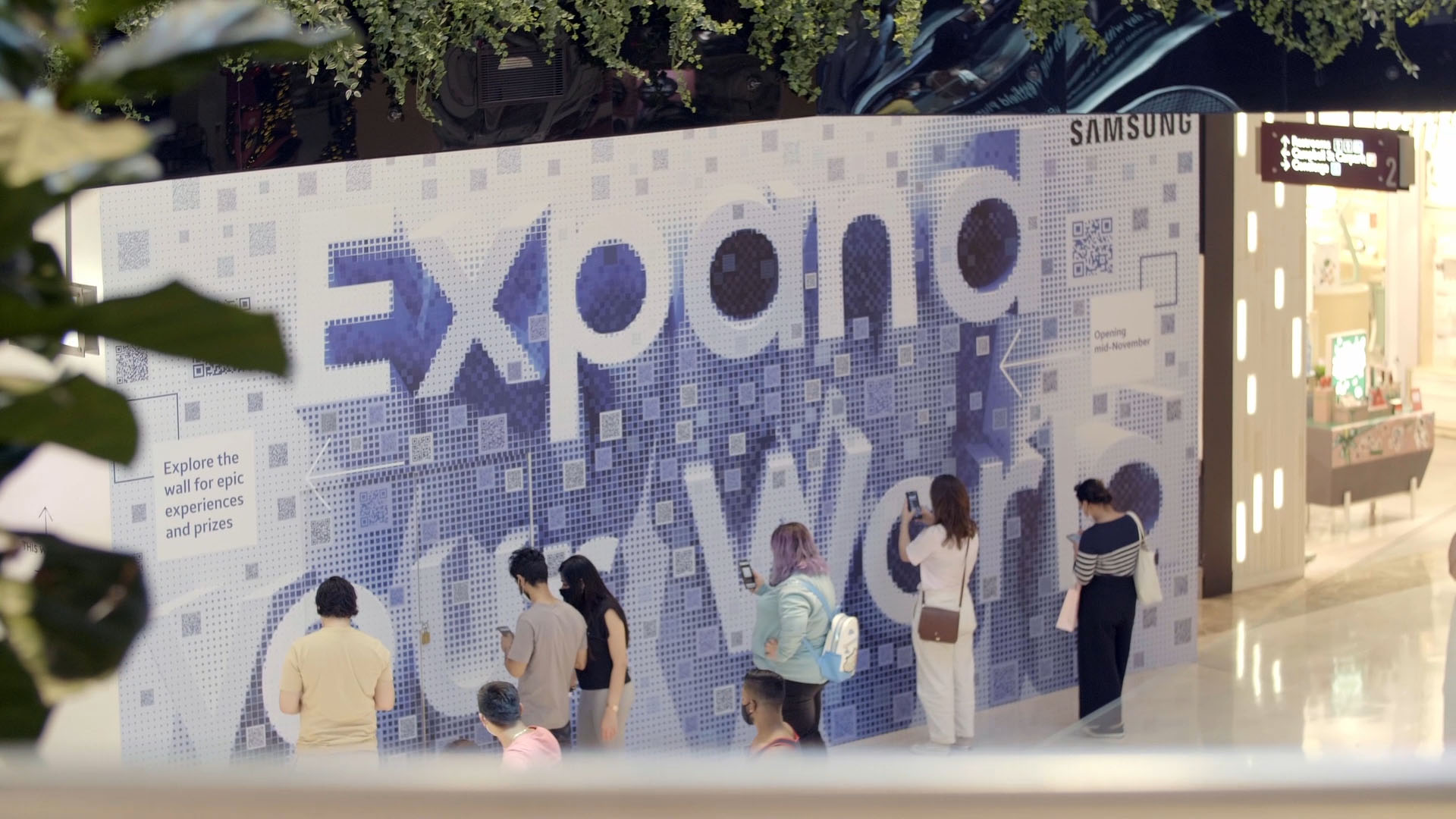 Shoppers interacting with a Sydney based experiential piece for Samsung featuring a mosaic of scannable QR codes that come together to say 'Expand our World'