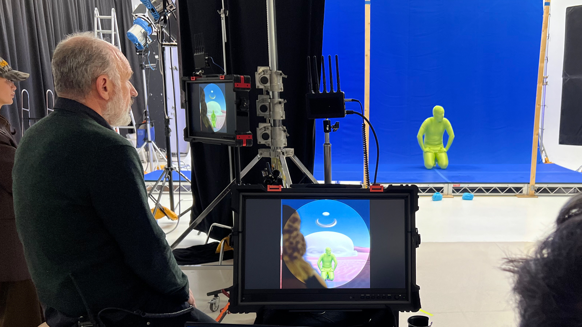 Person in green screen body suit in visual effects blue screen studio being filmed.