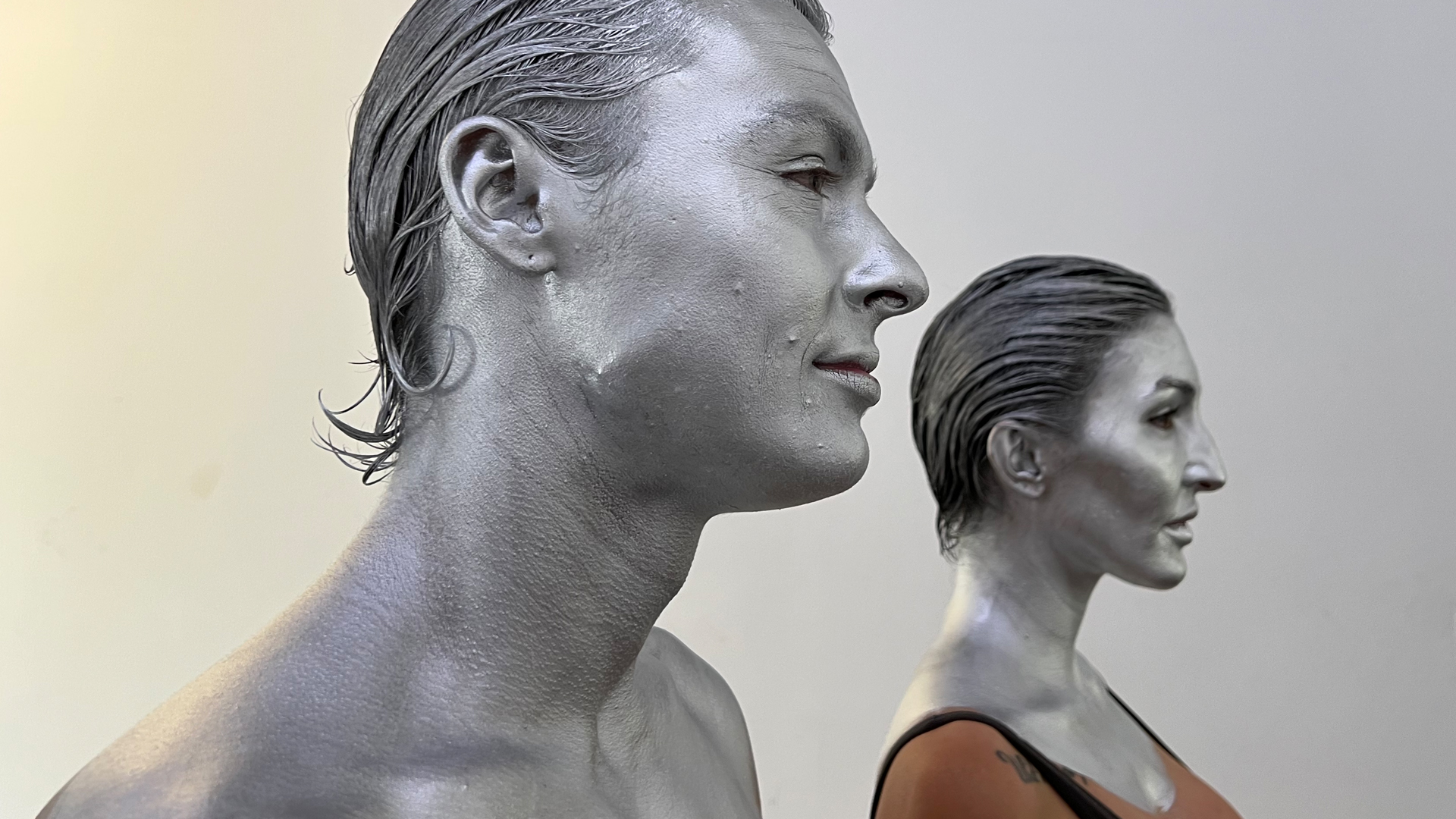 Close-up of man and woman painted in silver bodypaint