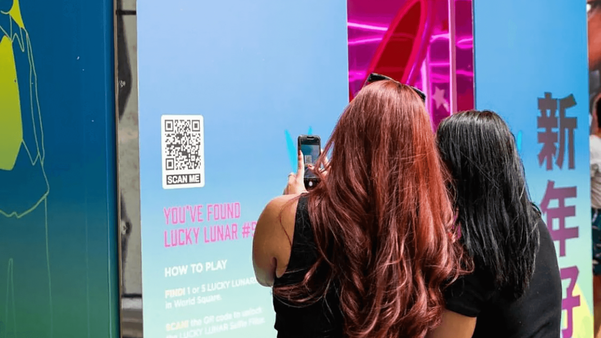 2 women scanning a QR code displayed on the Lucky Lunar experiential brand activation installation at World Square Sydney for Lunar New Year